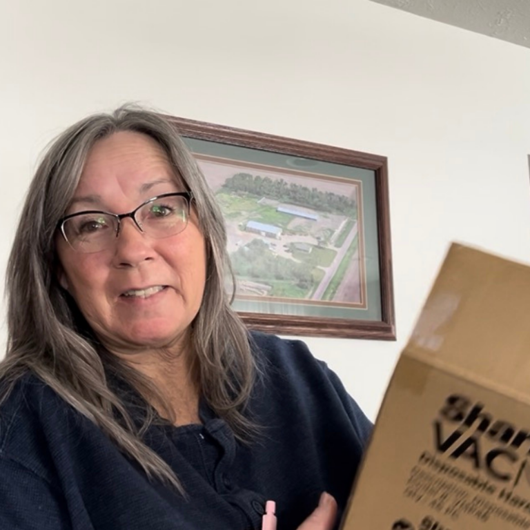 Cleo Schoenfelder holding a box of Shark VacMop replacement pads while sharing her experience using them in her home.